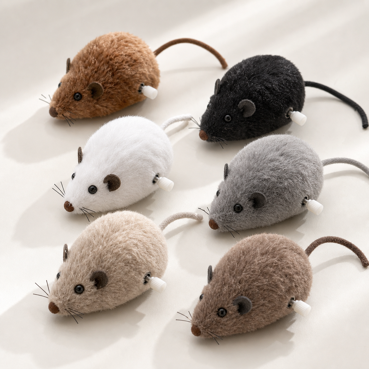 Set of plush wind-up mouse toys arranged on a clean studio surface